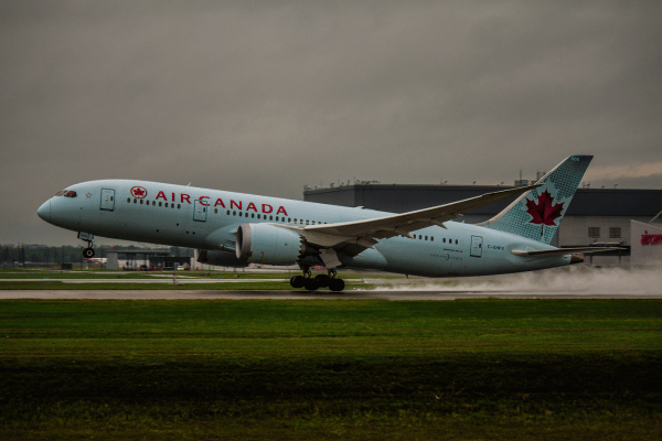 Air Canada airplane taking off from a runway on a cloudy day.