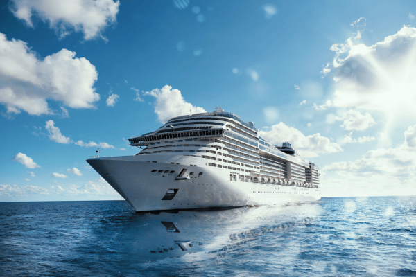 A large cruise ship sailing on the open sea under a bright, sunny sky.